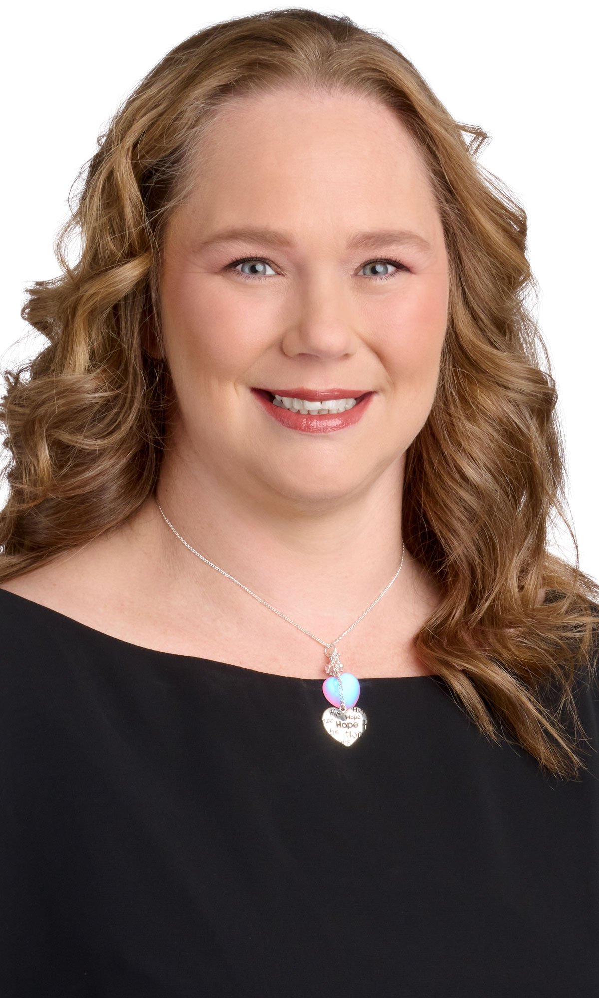 Chain necklace with glass and metal heart-shaped focals worn by a woman with long curly hair and a black shirt