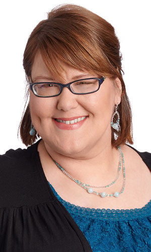 Woman showcasing a silver multi-strand chain necklace paired with icy blue beaded accents and matching teardrop dangle earrings.