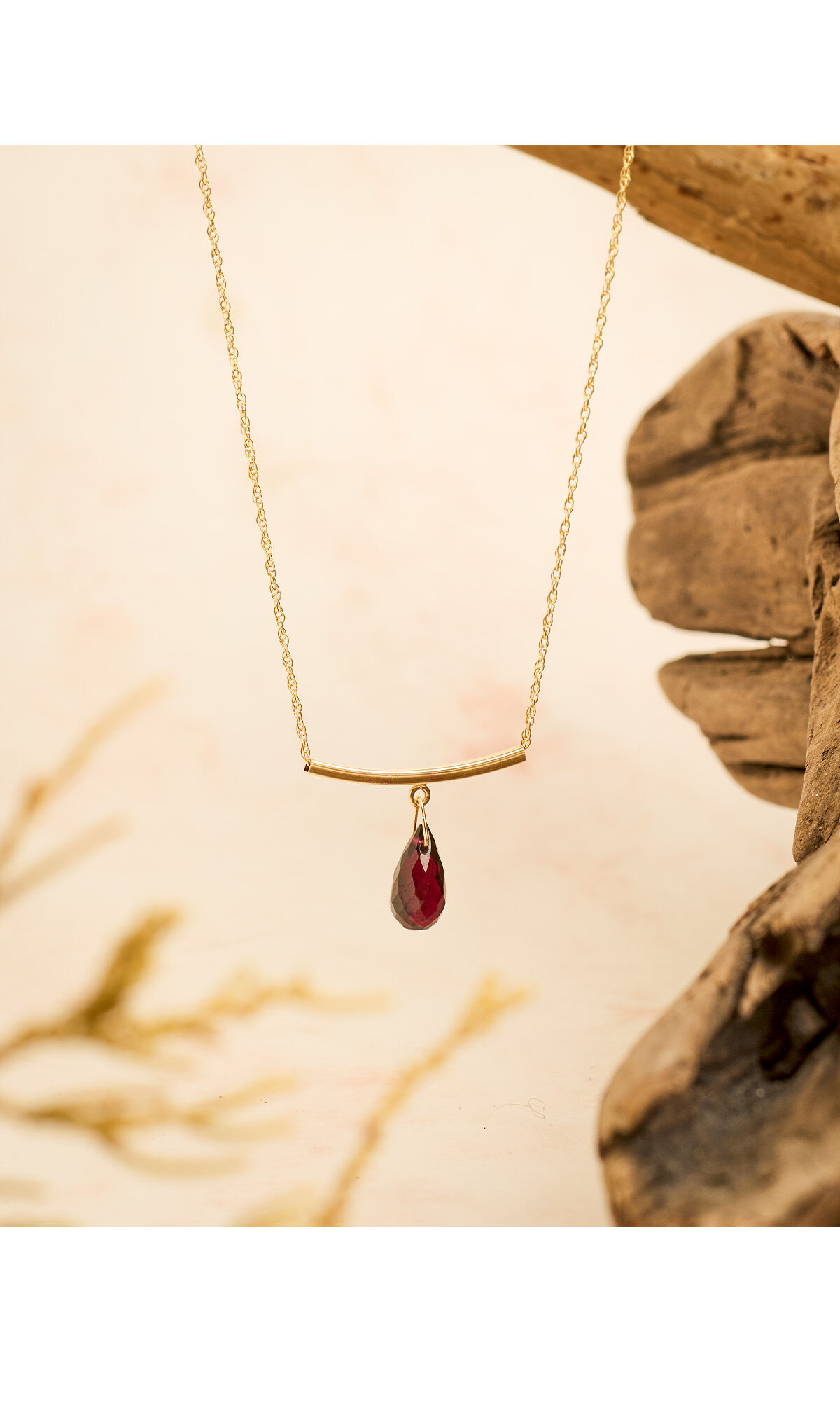 Design Idea R F 4 8 necklace hanging over a cream-colored background next to gnarled wood 