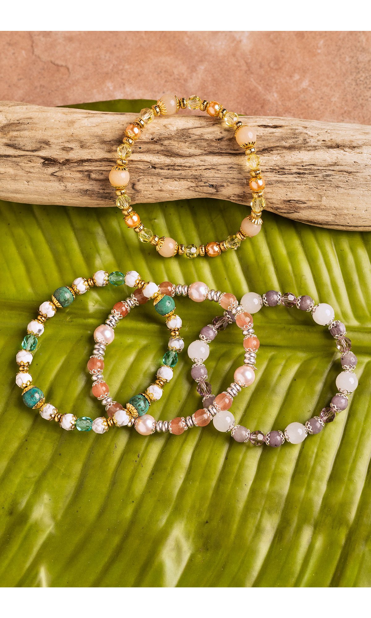 4 colorful bracelets displayed on dift wood and banana leaf