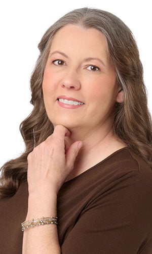 Woman wearing a brown top with hand on her chin showing Design Idea S A 2 G Memory wire bracelet with metallic gold- and silver-hued beads
