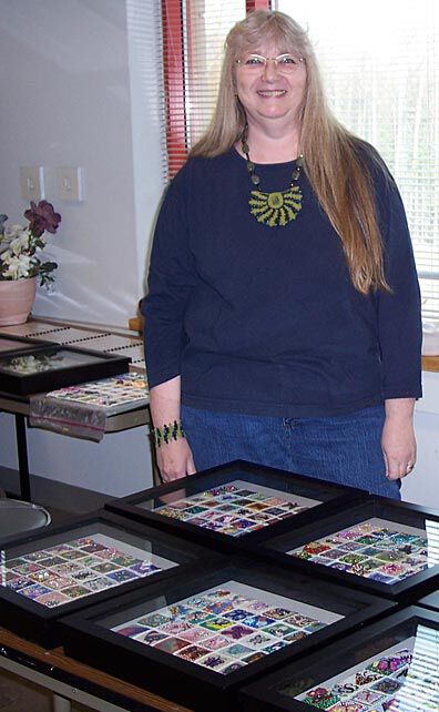 Jeanette standing next to beaded quilts in display cases