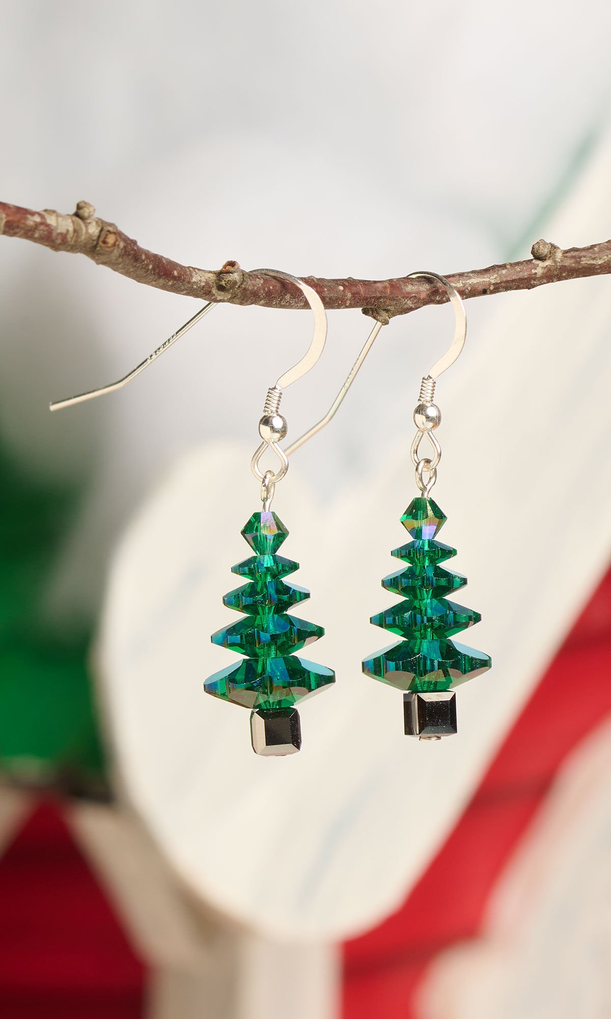 Stylized view of fishhook earrings with Christmas trees made out of green disc beads