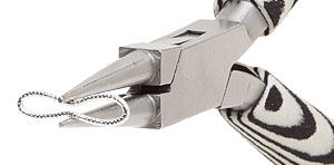 Pliers pinching the center of the stretched jump ring