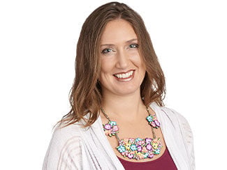 Woman wearing polymer clay necklace E B 0 F featuring bright flower clusters made using polymer clay canes. Two small clusters on the mid-left and mid-right, one wide cluster in the center front, all on a multi-strand seed-beaded necklace.