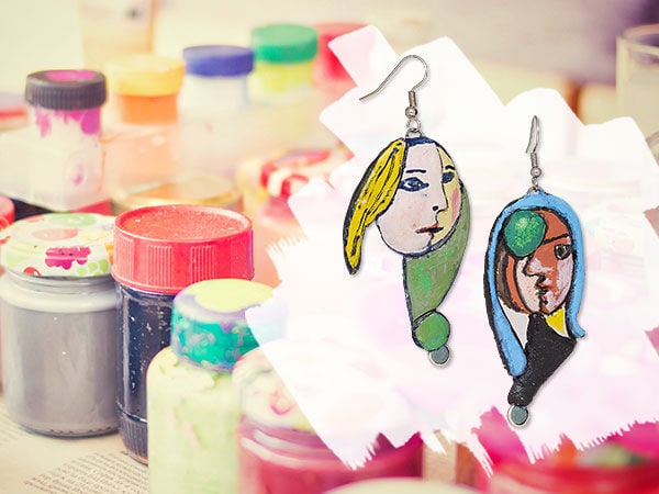 Multicolored jars and bottles of pain with two cubist-inspired portrait earrings in the foreground
