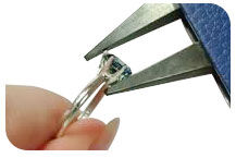 A gem is being set in a prong-setting using pliers.