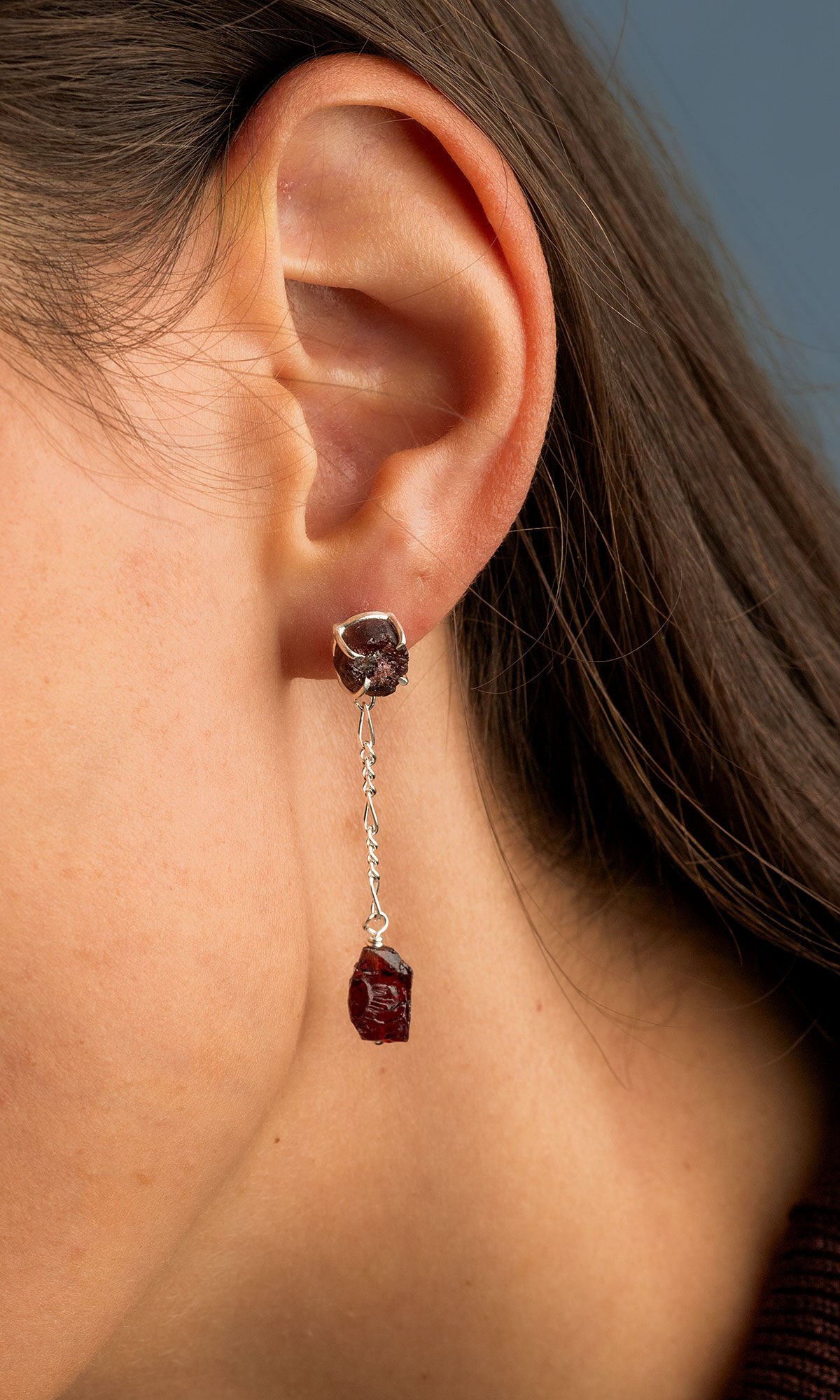 close up of model's ear wearing Design Idea S A 2 2 Garnet nugget stud earrings with another garnet nugget suspended from delicate chain