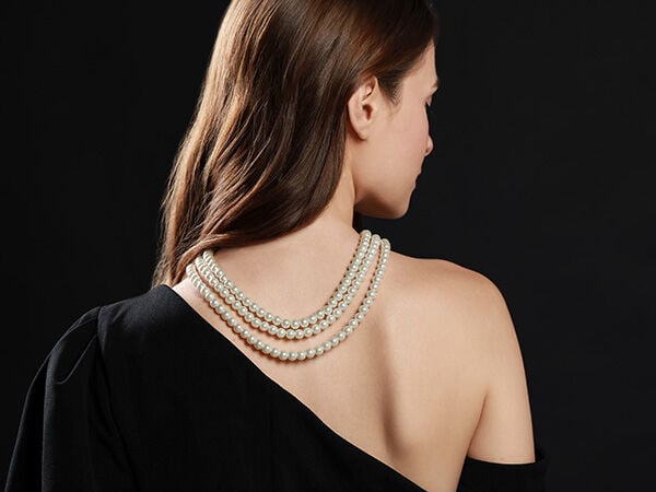 Model wearing a backdrop necklace of three strands of white pearls