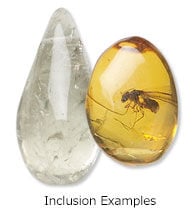 Two polished gemstones side-by-side: a clear teardrop-shaped crystal on the left, and an oval amber stone containing a fossilized insect inclusion on the right.