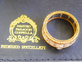 Buccellati logo next to a gold ring with a central diamond and smaller diamonds all over the band.