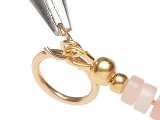 Step 7 showing an open jump ring with a wire protector and toggle clasp being added to it