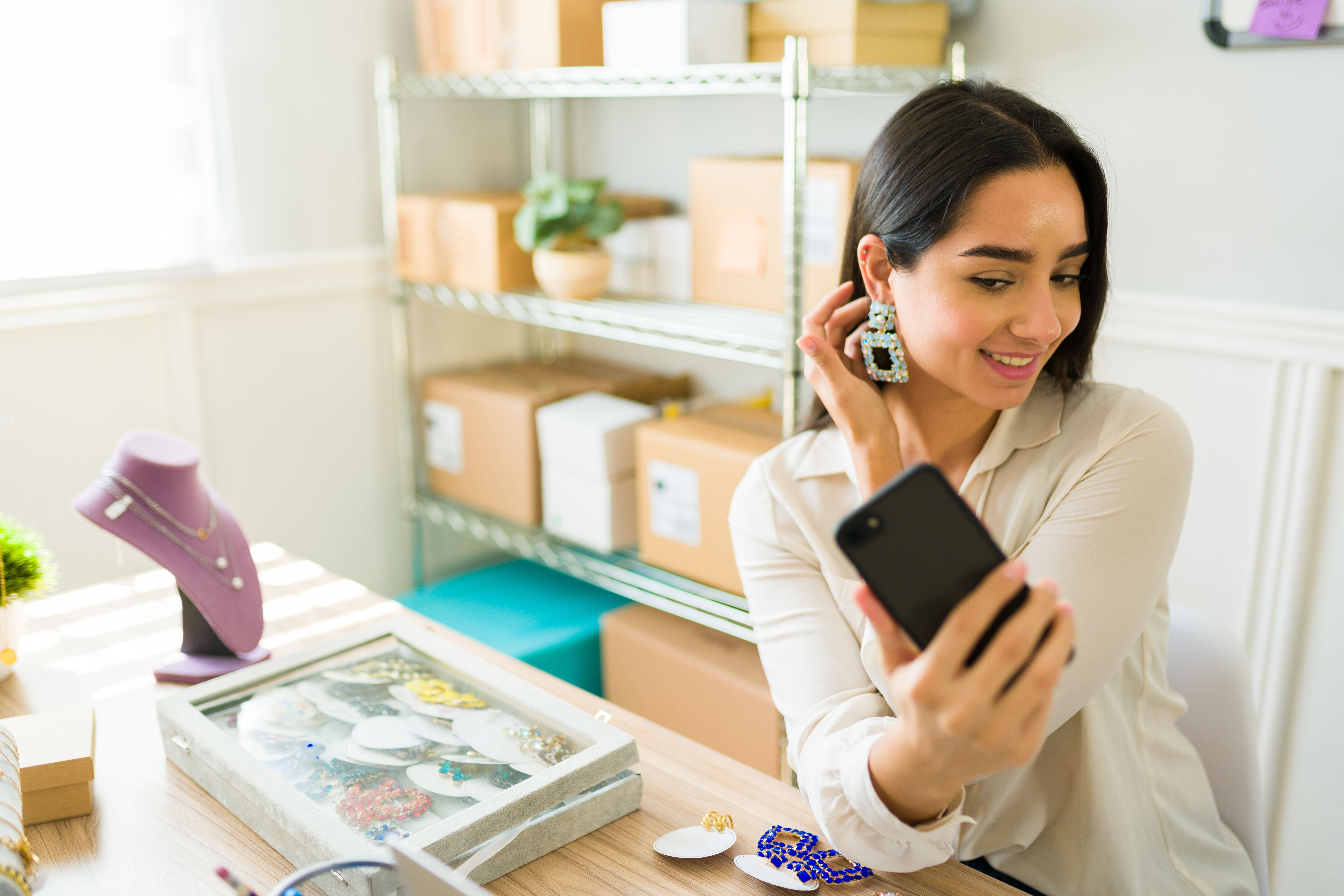 Woman trying earrings on while looking at her phone