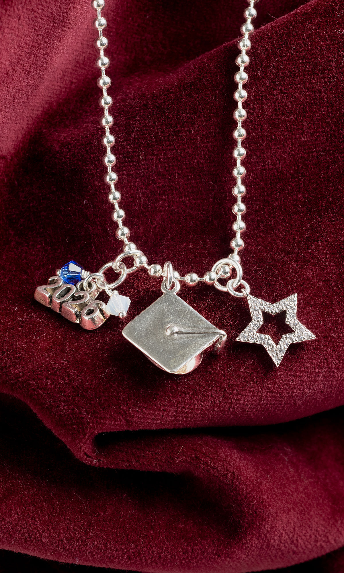 Necklace hanging in front of dark red fabric