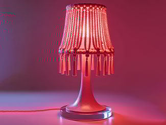 A red LED lamp with a decorative beaded shade illuminated in a dark setting.