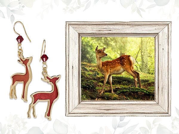 On the right, a gray wood frame surrounds an image of a deer in a sunlit forest. On the left is a pair of golden earrings with brown and golden deer charms.