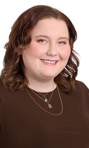 Model wearing brown blouse modeling layered necklace set