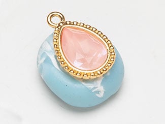 Pink stone is in teardrop setting, still atop blue clay