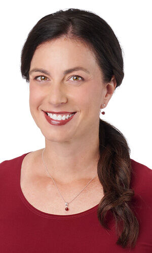 Design Idea R B 2 K - A smiling woman wearing matching maroon bead drop earrings, and a coordinating pendant necklace.