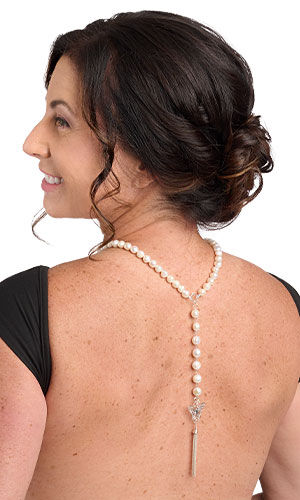 Design idea R G 2 X: Back view of a choker-length pearl necklace with a strand of seven large pearls with a silver butterfly and chain tassel at the end dangling from the center back of the necklace 