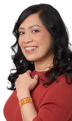 woman in a red top with hand on chest wearing a Design Idea Q G 2 K Bracelet with Delica&reg; Seed Beads and Gold-Finished "Pewter" Enameled Charm