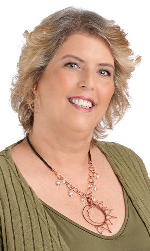 A smiling woman in green wearing design Idea N H 2 Z