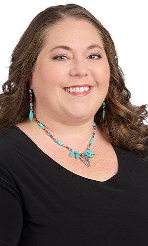 model in a black top wearing Design Idea R K 2 8 - Necklace has a large silver arrowhead at the center, surrounded by blue marquise gemstone drops and blue, red and silver beads. Earrings have blue, red and silver beads with a blue marquise gemstone drop at the bottom.