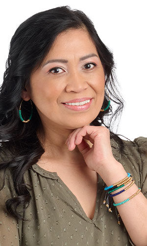 A smiling woman in green wearing Design Idea R D 2 T