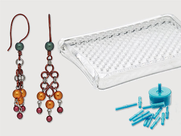 Red wire chandelier earrings with orange, red and green beads next to a clear wire jig and light blue pegs