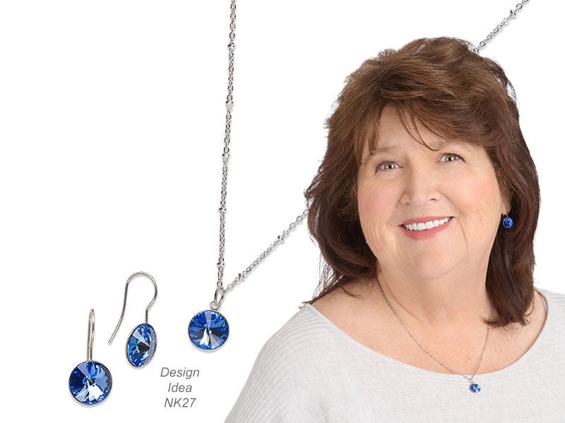 Model wearing a necklace and earrings with sapphire colored crystals