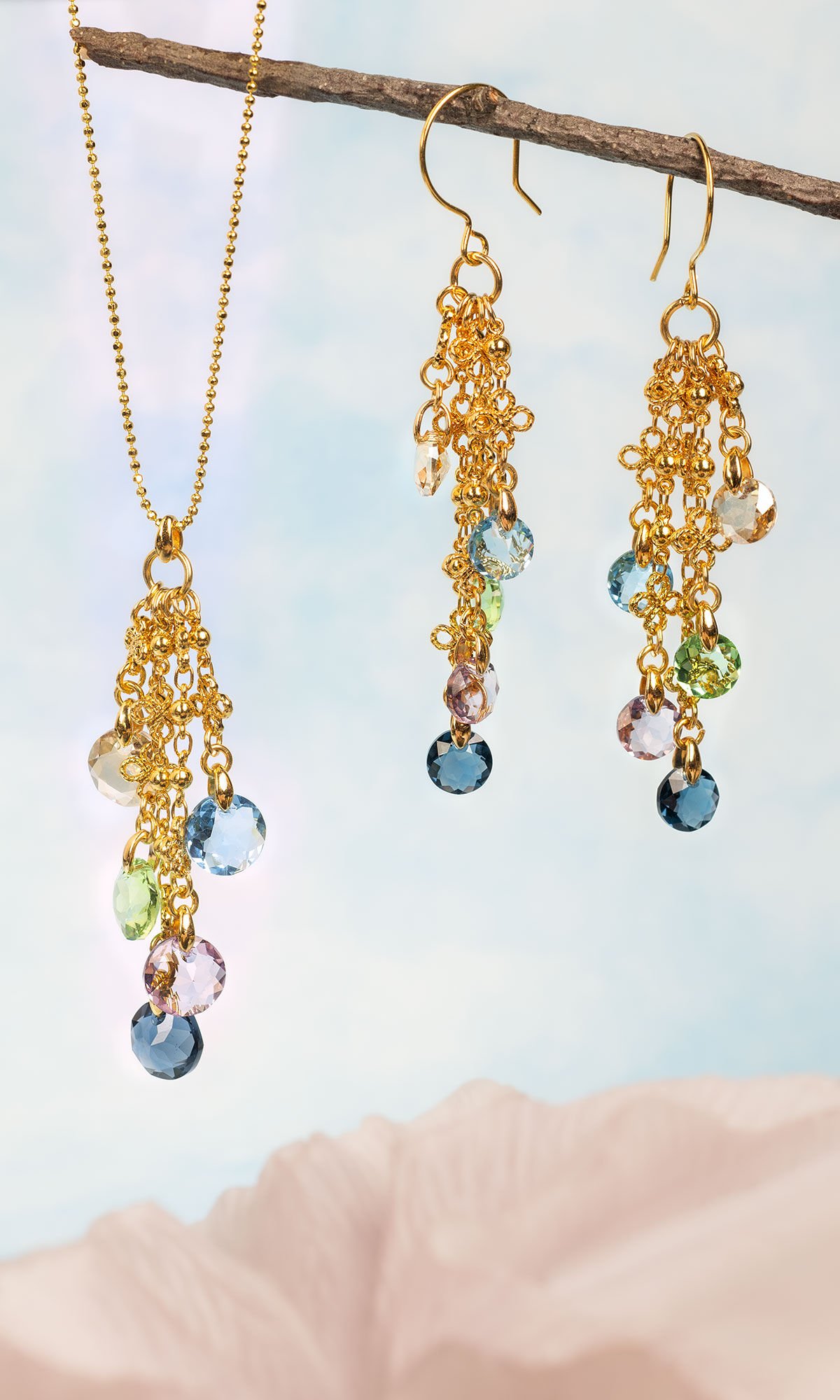 Design Idea R K 2 C hanging off of a wooden branch with blue background and light pink at the bottom of image.