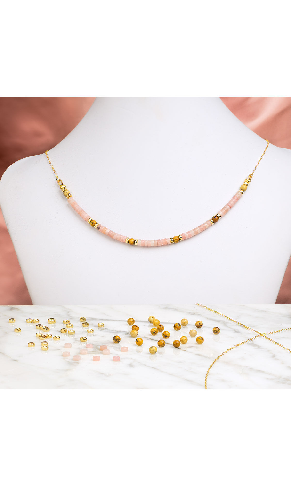 Design Idea R G 2 8 Lower half of necklace has smooth pink heishi beads and occasional gold and jasper beads in a strand suspended from gold chain. with pink satin fabric behind the necklace but and the components on a marble table in front