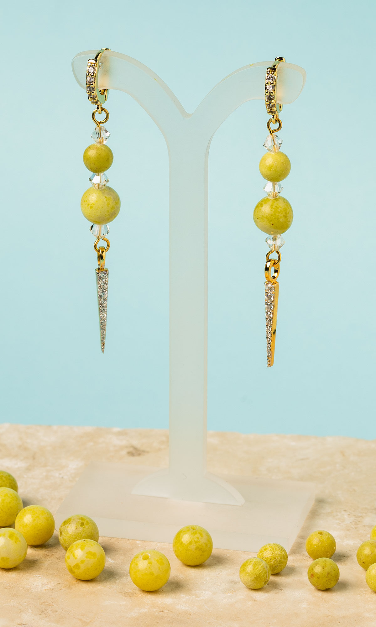 Earrings hanging from acrylic display with loose beads on the table surface