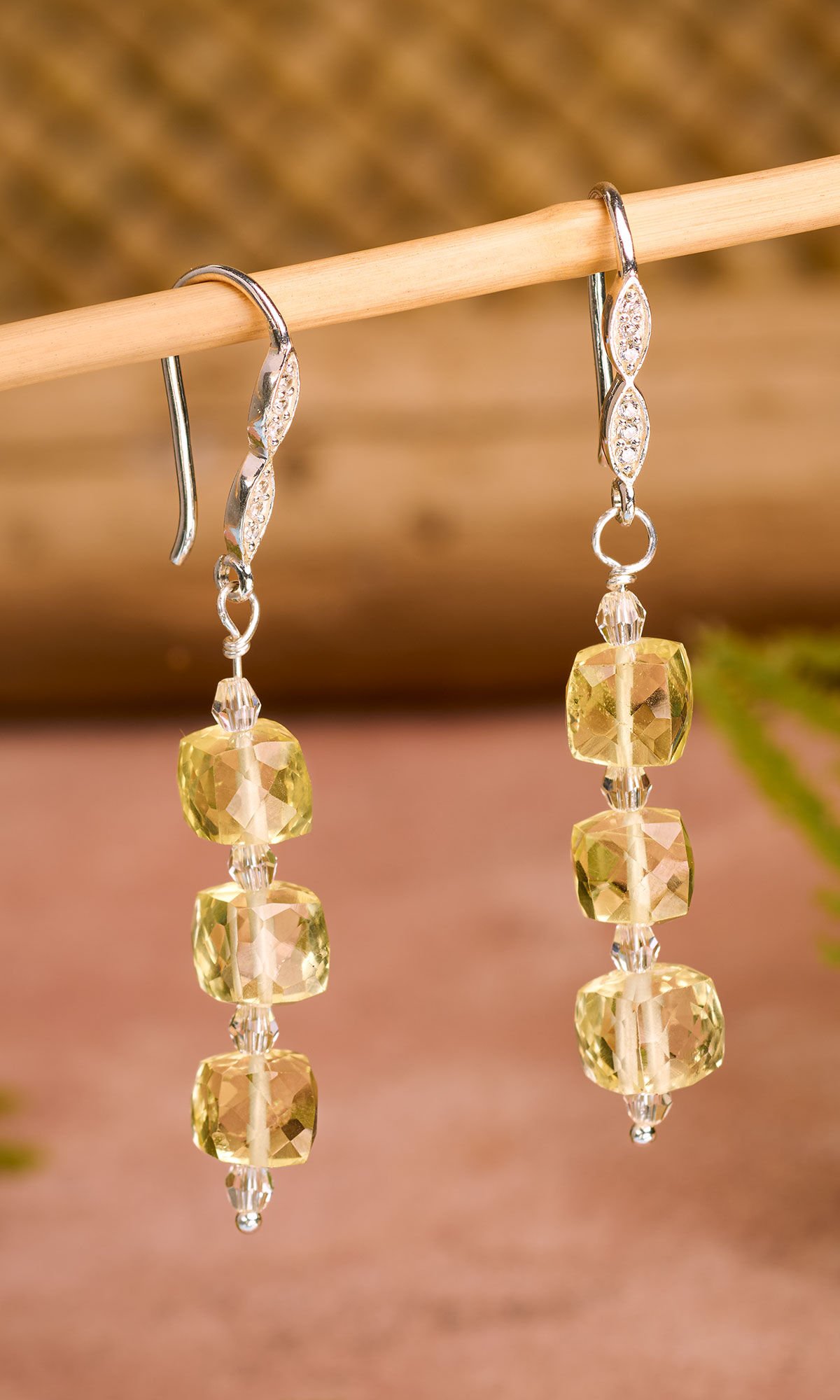 Design Idea R F 4 7 - Fishhook earrings with three yellow dangling gemstone square beads separated by small clear faceted beads against a natural background