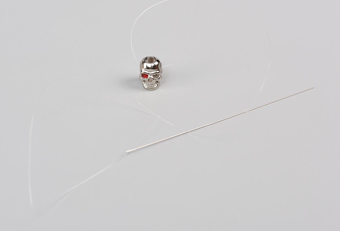 Skull bead showing needle and thread adding red beads for eyes