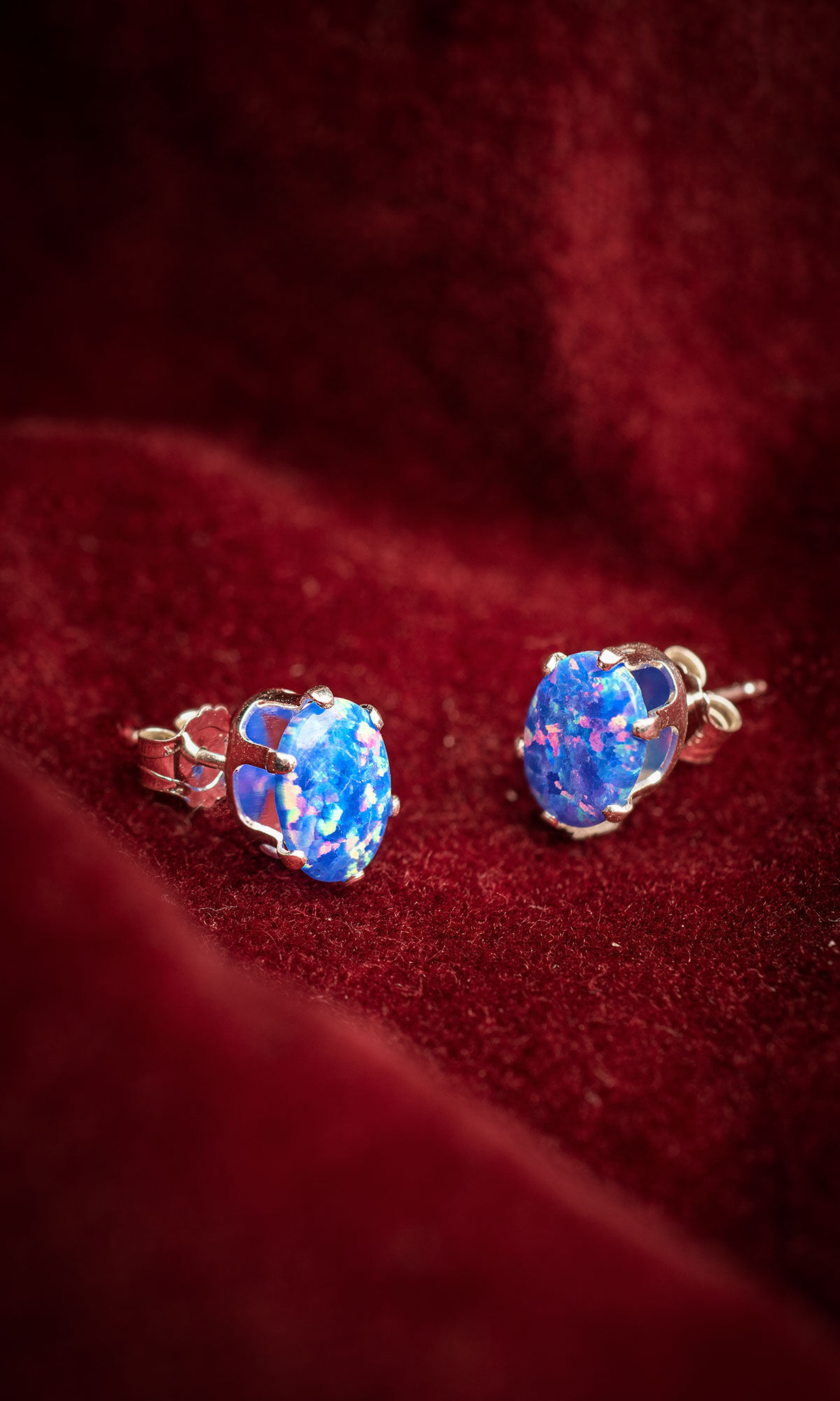 Beautiful opal stud earrings on velvet red flowing material