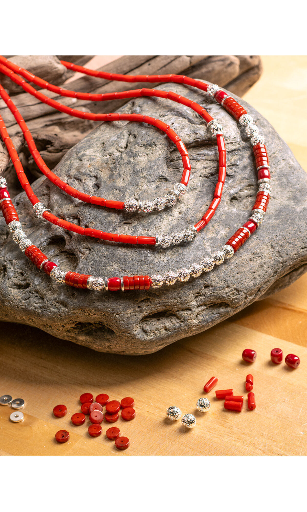 Design Idea R D 3 7, necklace draped over a stone on a hard wood floor, silver and coral beads laid out on floor