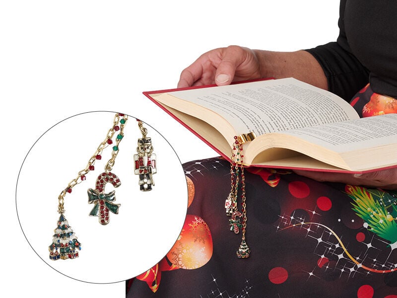 A person sitting holding an opened book with a bookmark made with christmas charms