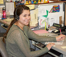 Woman wearing a headset writing on a piece of paper