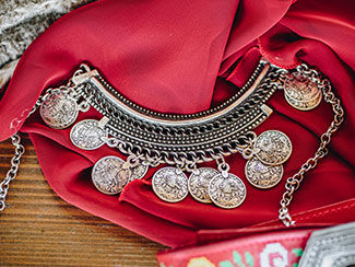 Chain with silver coins hanging from it against a red cloth background