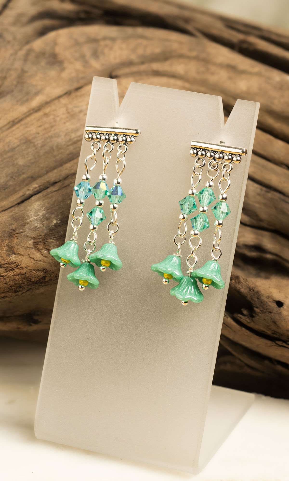 Earrings displayed on card in front of driftwood log