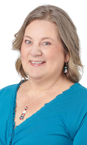 Woman accessorized with multi-colored pendant necklace featuring stacked geometric blocks and a matching dangling earring with turquoise accents.