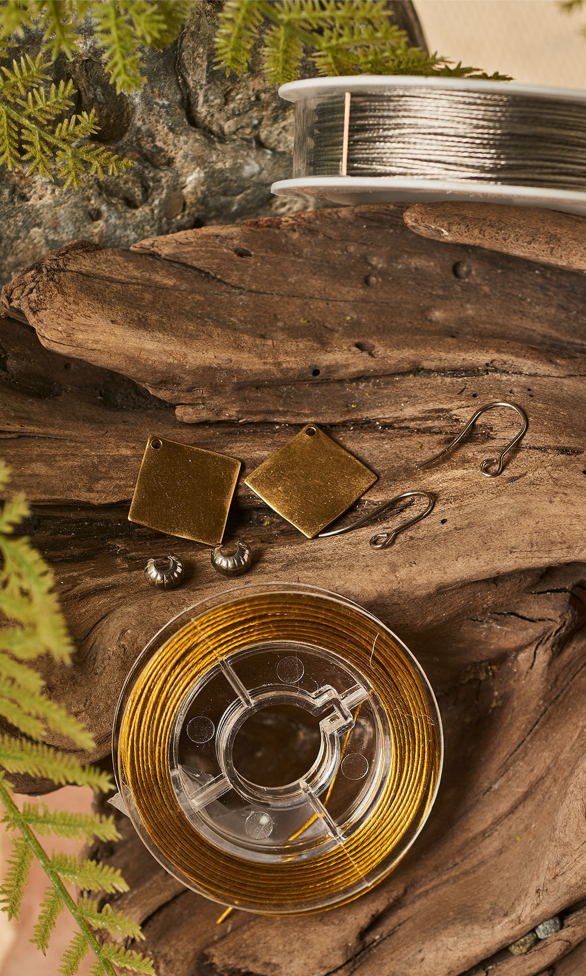 wire spools and earring components laid out on a slab of wood