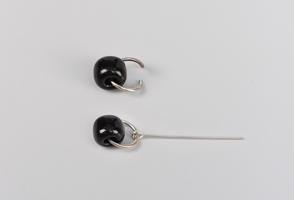 Two black beads showing how to attach jump rings and eye pin