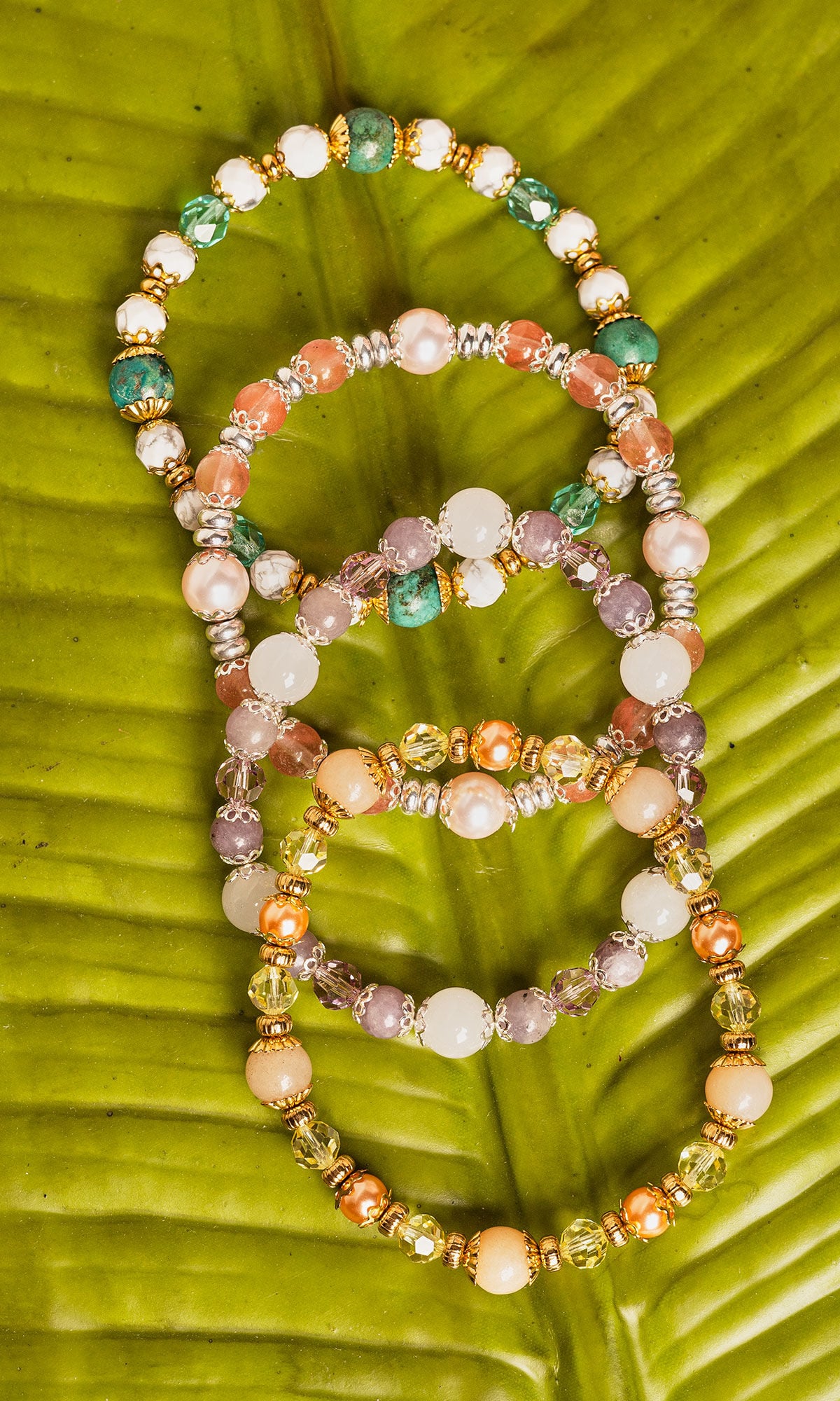 4 colorful bracelets displayed on banana leaf