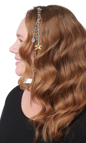 Design Idea S H 2 C &ndash; Profile of woman featuring a spiral hair charm wrapped around a small braid. The metallic coil jewelry is adorned with hanging beaded strands, a small cowrie shell, and a yellow starfish pendant.