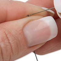 Fingers are threading a needle.