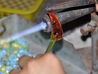 Shaping heated glass with tongs