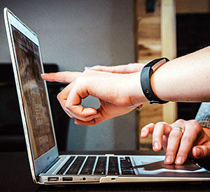 Hands pointing to a laptop computer