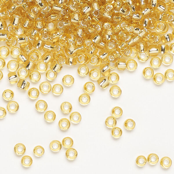 Seed bead, Dyna-Mites™, glass, silver-lined translucent light gold, #8 round. Sold per 40-gram pkg. image number 0